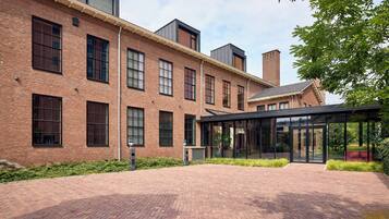 A brick building with large windows and a covered outdoor area.