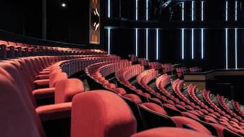 Een theater met rijen rode stoelen, een groot verlicht bord en een modern ontwerp.