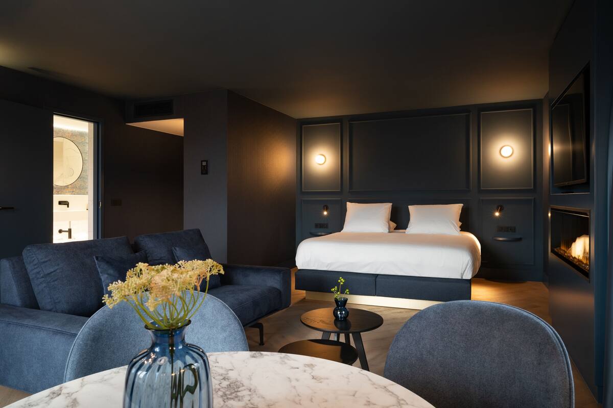 Ein modernes Hotelzimmer mit einem Bett, einer Couch, einem kleinen Tisch und einer Blumenvase.