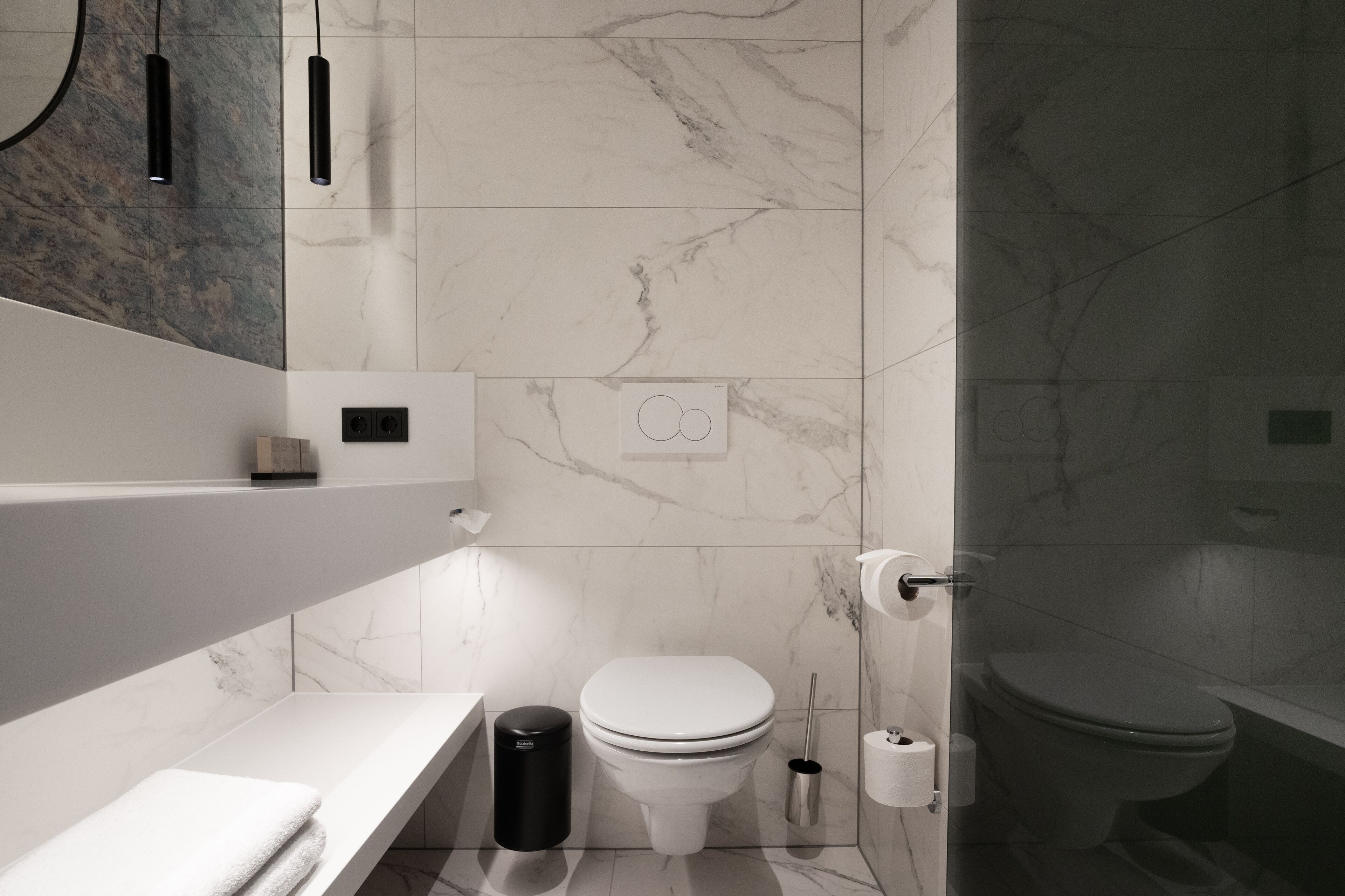 A modern bathroom with a white toilet, a sink, and a mirror.