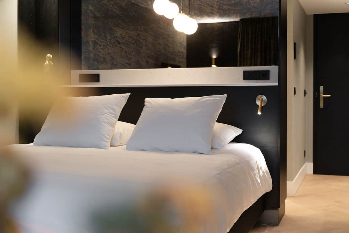 Ein modernes Schlafzimmer mit einem großen Bett, einem dunklen Kopfteil und einer Wandleuchte.