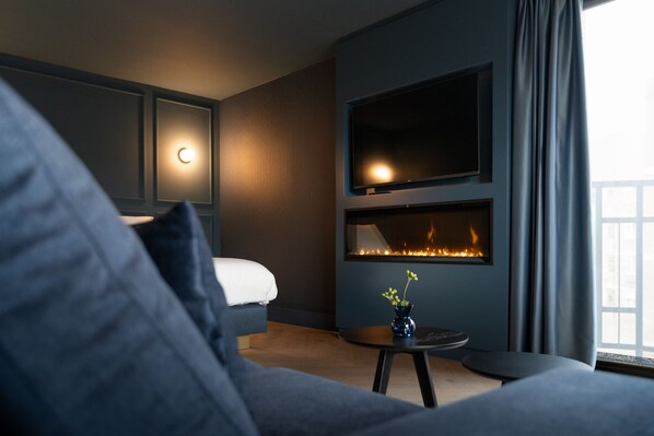Ein modernes Wohnzimmer mit Kamin, einer Couch und einem an der Wand befestigten Fernseher.