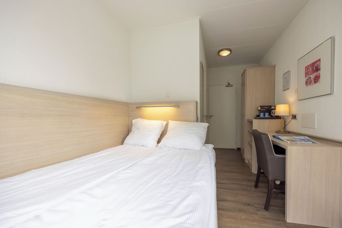 Hotellihuone, jossa on sänky, työpöytä ja tuoli.