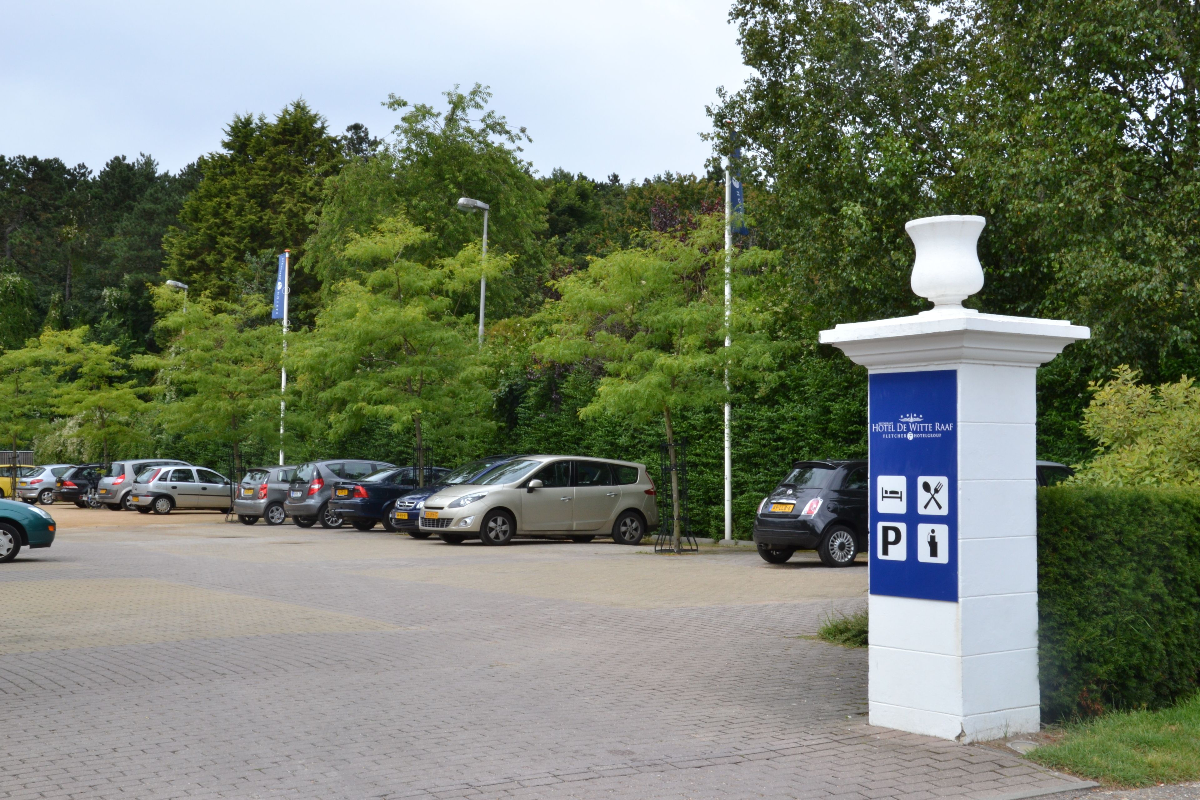 A parking area with cars and a sign indicating hotel services.