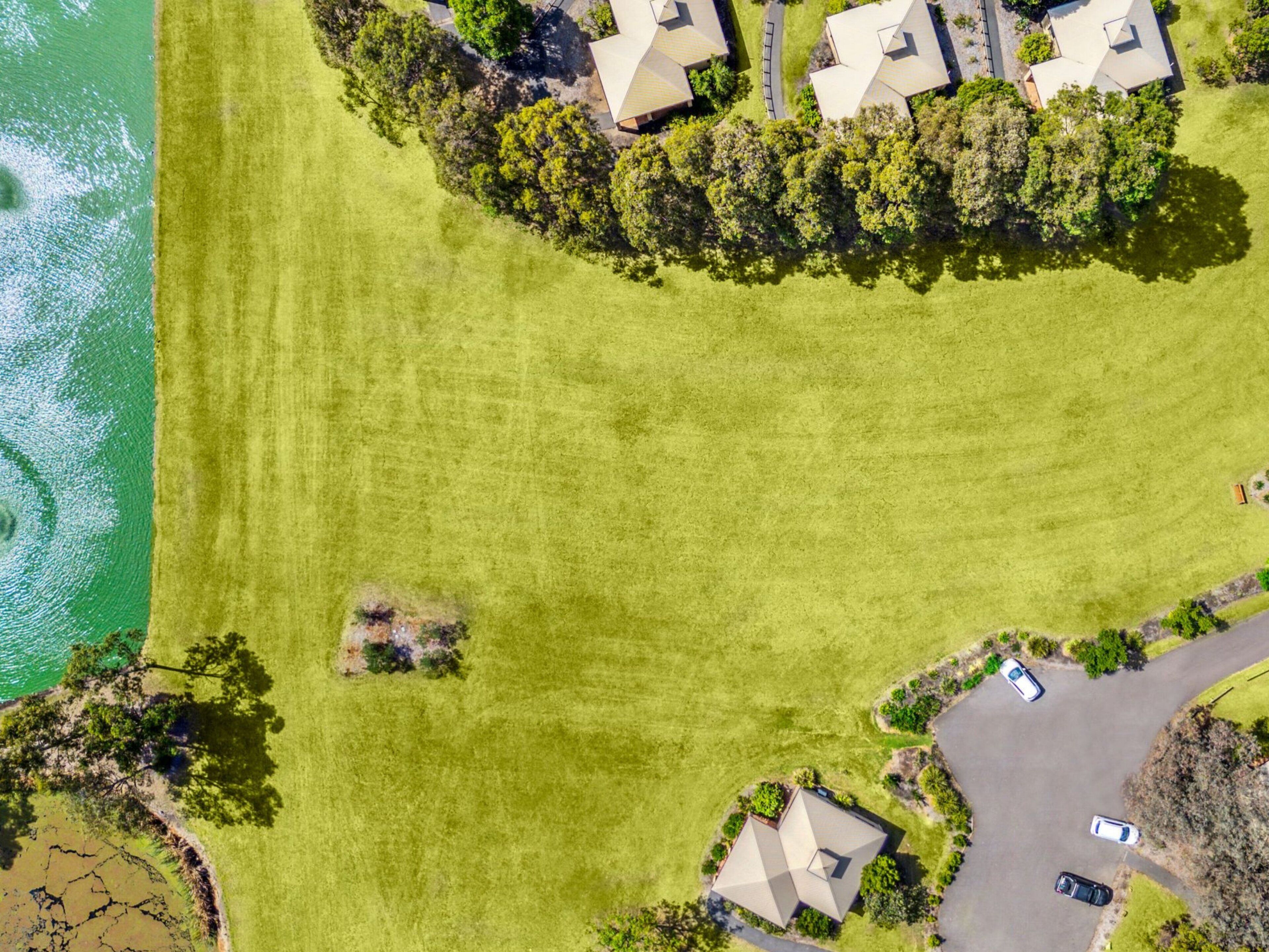 An aerial view of a residential area with houses, a road, and a body of water.