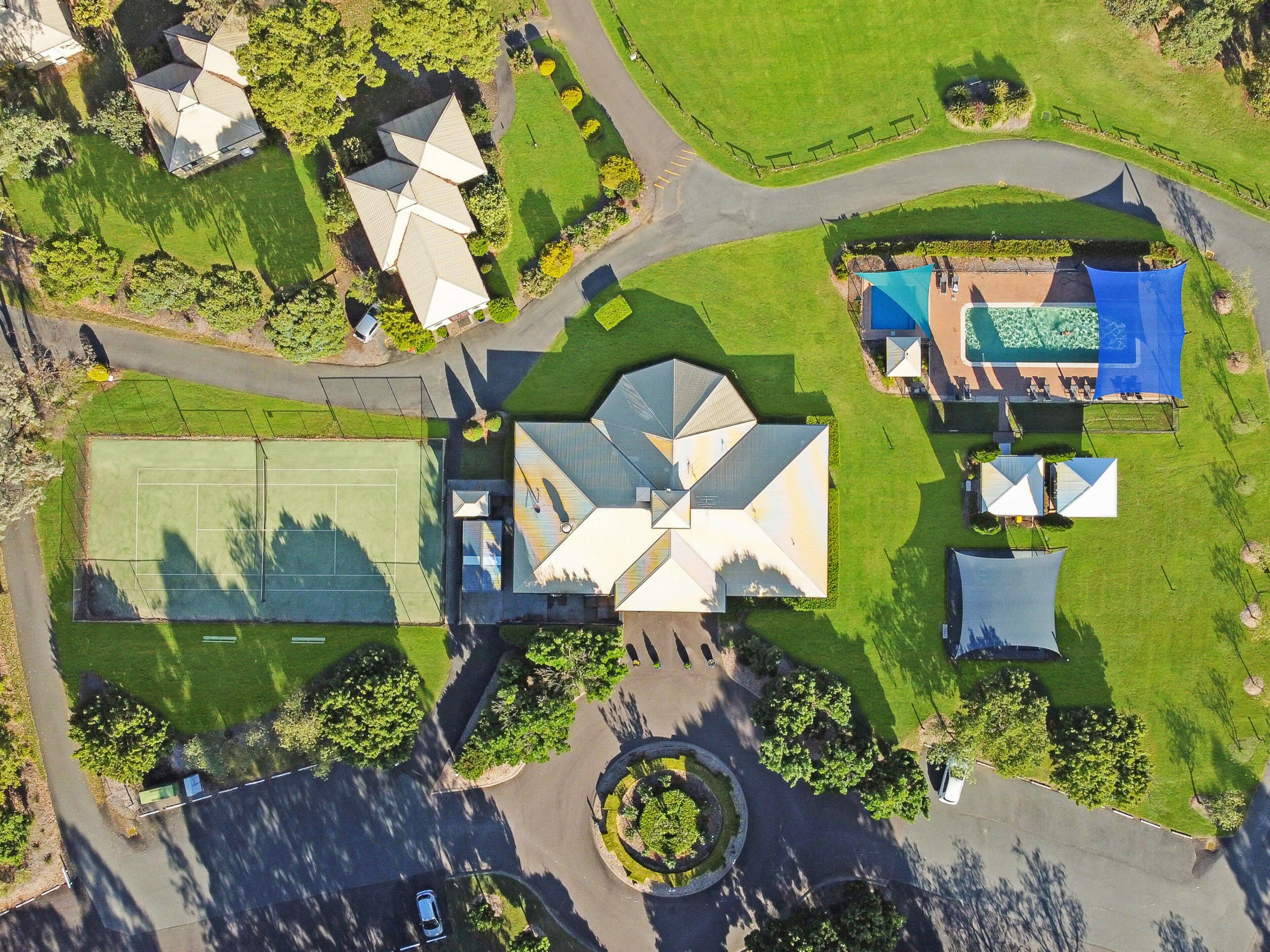 Vista aérea de una zona residencial con varias casas, una cancha de tenis y una piscina.