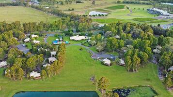 An aerial view of a golf course with multiple buildings, a pond, and surrounding greenery.