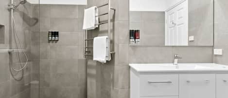 A modern bathroom with a glass-enclosed shower, a white vanity with a sink, and a large mirror.
