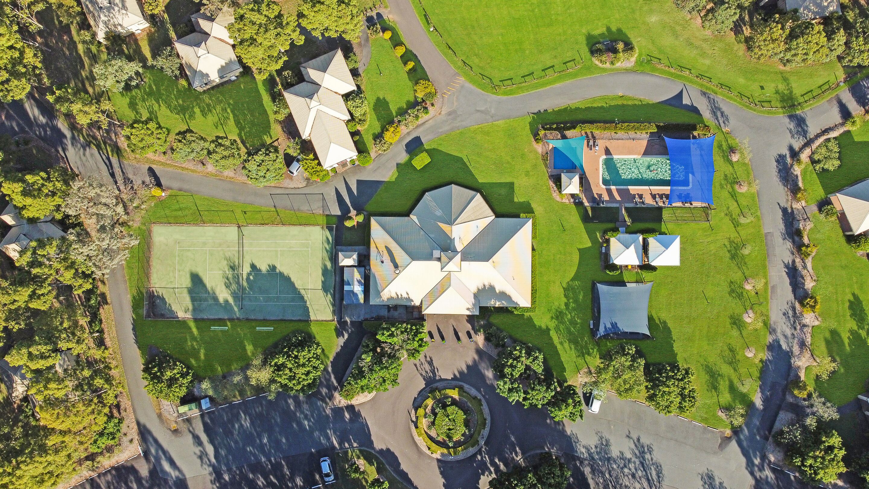 Vista aérea de una zona residencial con casas, cancha de tenis y piscina.