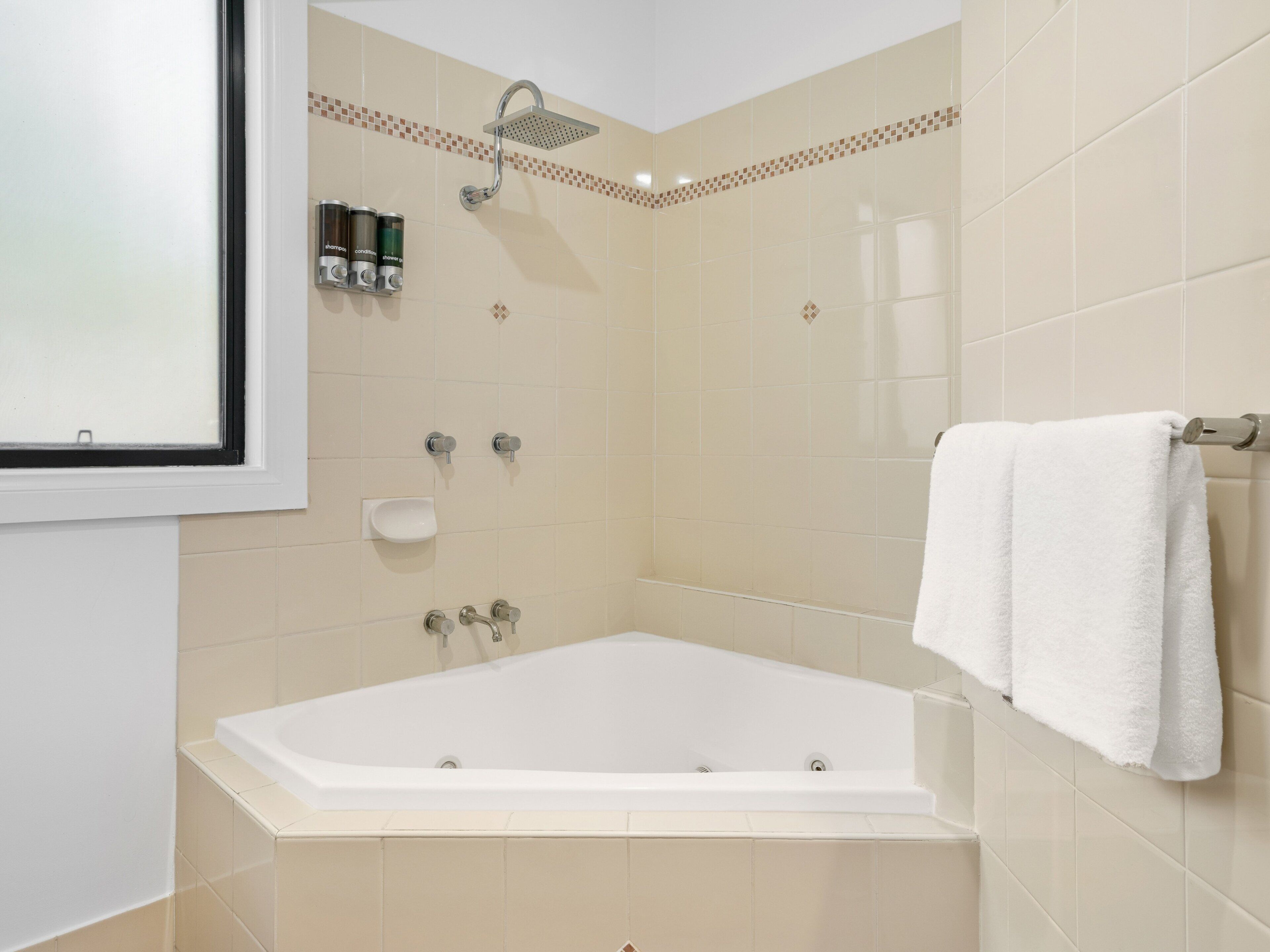 Un baño moderno con bañera, ducha y dos dispensadores de jabón para manos.