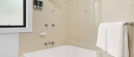 Un baño moderno con bañera, ducha y dos dispensadores de jabón para manos.