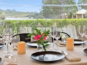 A table set for dining with a view of a vineyard and a building in the background. - Leisure Inn Pokolbin Hill (Pokolbin)
