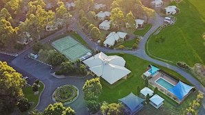 Vista aérea de un área residencial con casas, una cancha de tenis y una piscina.