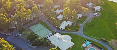 An aerial view of a residential area with houses, a tennis court, and a swimming pool.