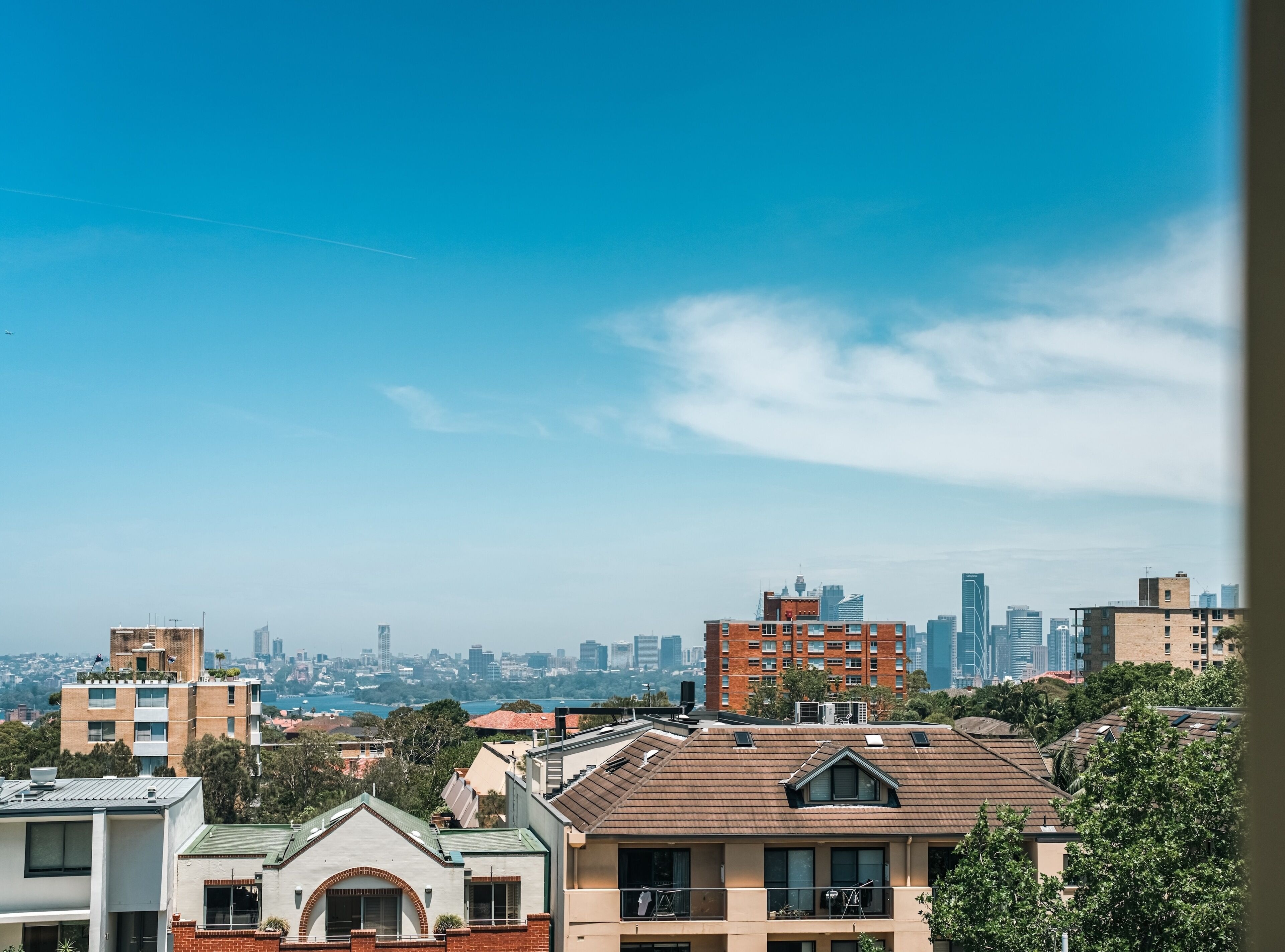 A cityscape with a mix of residential and commercial buildings, including a prominent red brick building and modern skyscrapers in the background.
