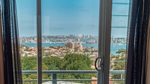 Vista desde una ventana con vista a una ciudad costera, con edificios, árboles y una masa de agua.