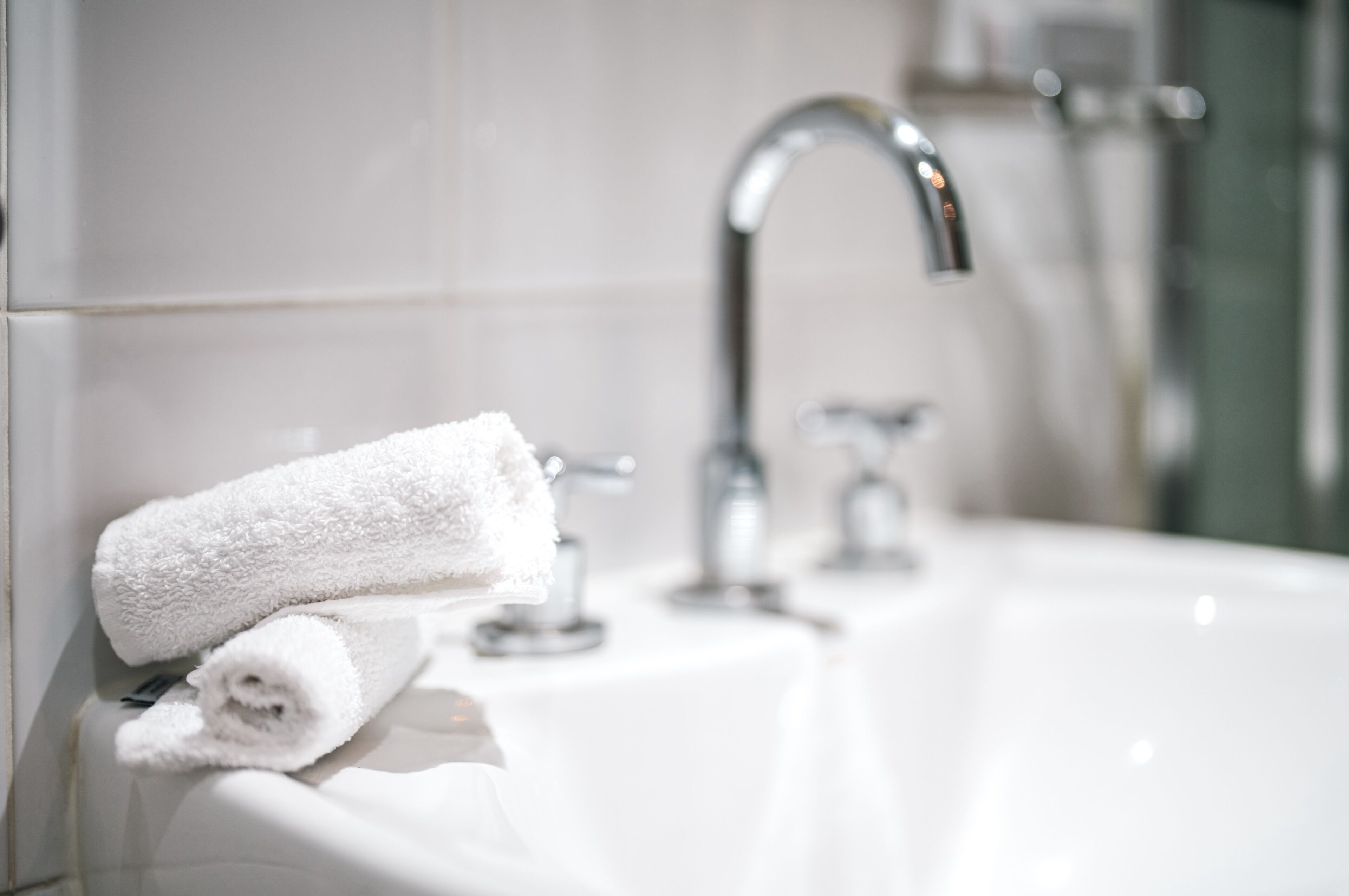 Ein Badezimmer mit einem weißen Waschbecken, einem Handtuch und einem Chrom-Wasserhahn.