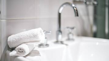 Ein Badezimmer mit einem weißen Waschbecken, einem Handtuch und einem Chrom-Wasserhahn.