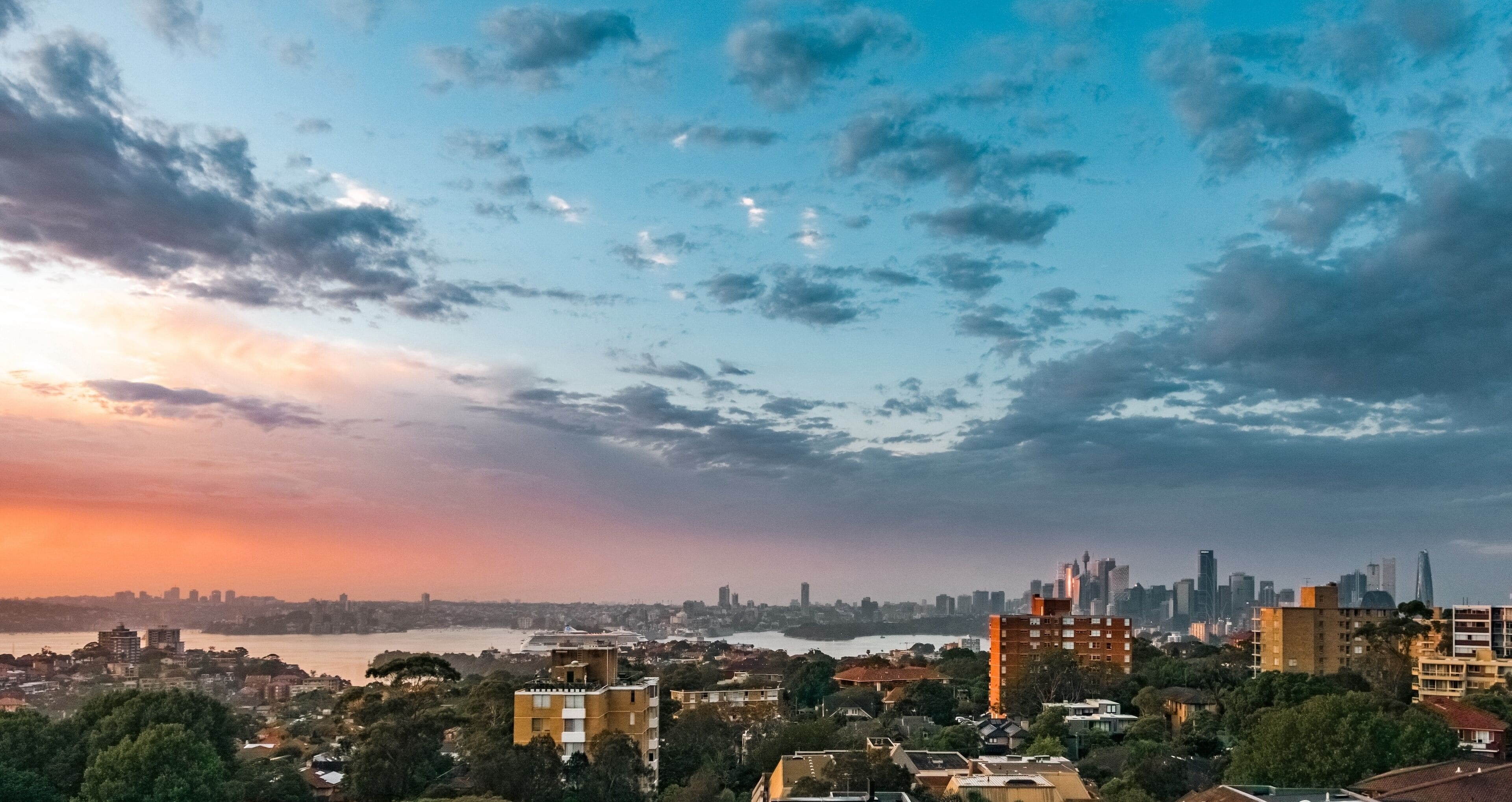 Un paisaje urbano con un río, edificios y un cielo al atardecer.