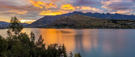 A lake with mountains in the background and a residential area in the foreground.