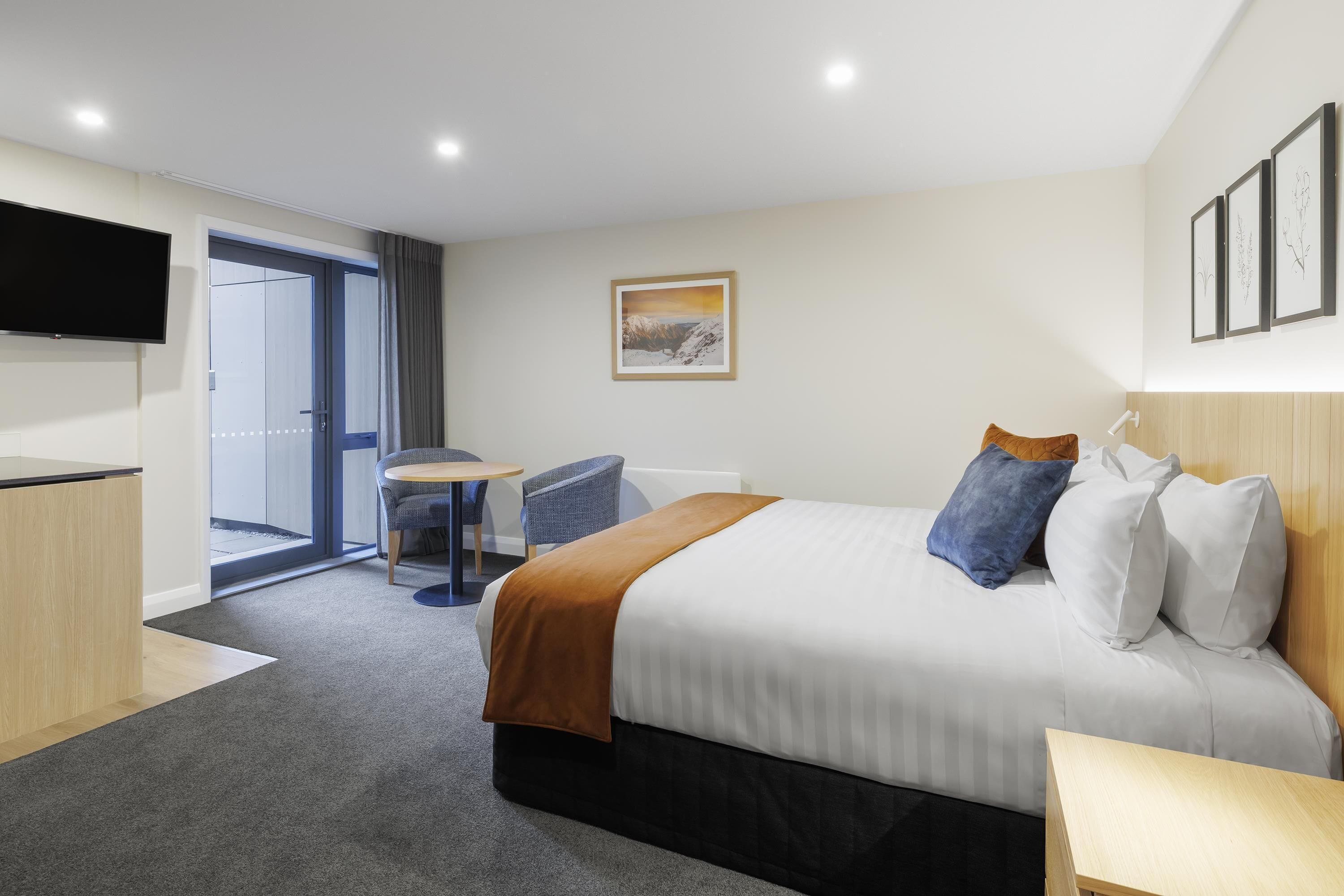 Ein modernes Hotelzimmer mit einem großen Bett, einem Schreibtisch, einem Stuhl und einem Fernseher.