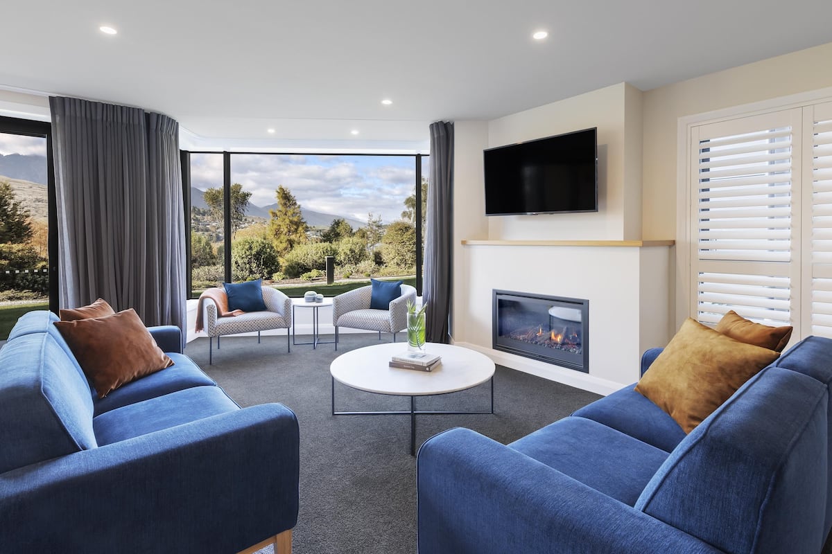 Una sala de estar moderna con chimenea, ventanas amplias y un televisor de pantalla plana.