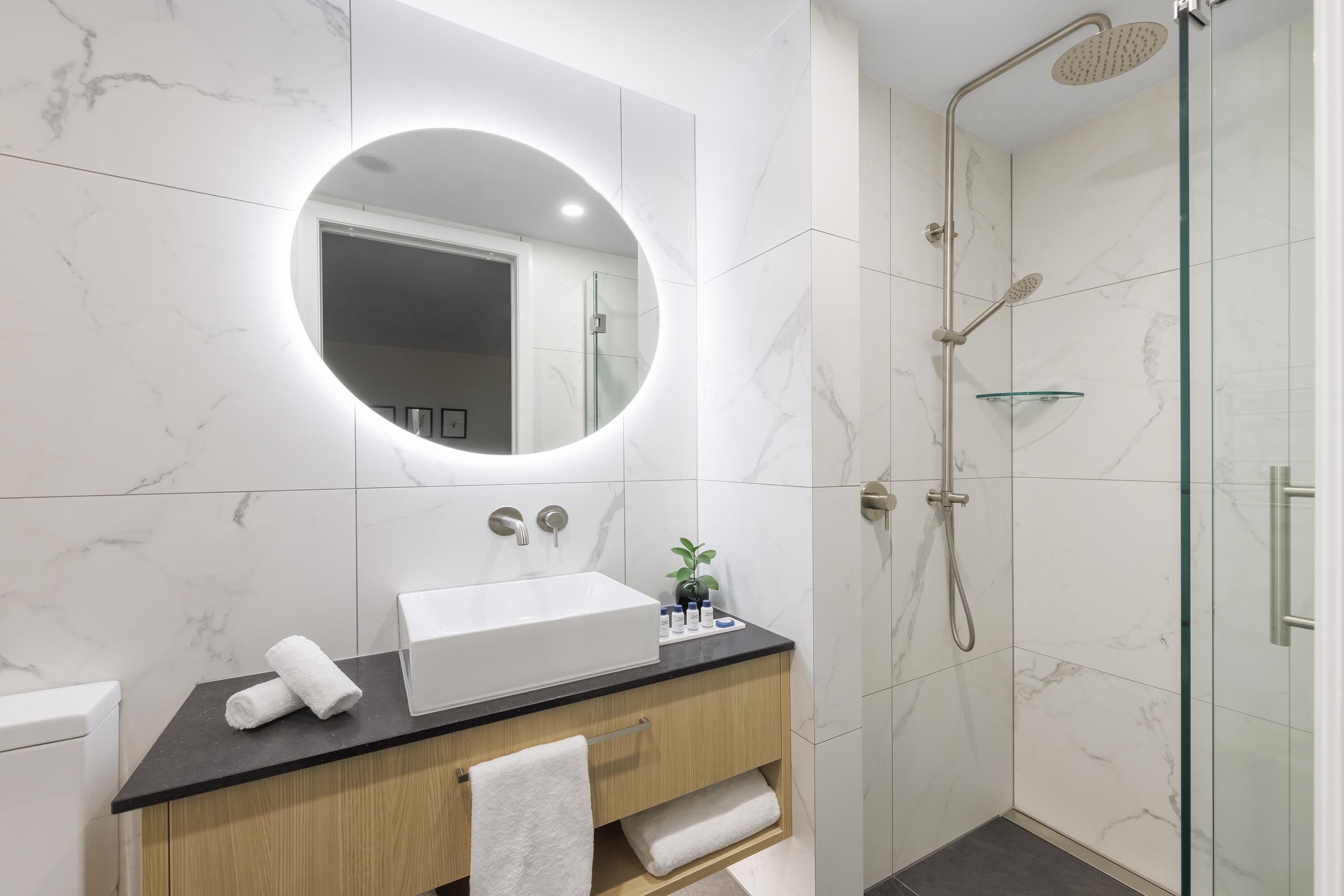 Un baño moderno con un espejo grande, un lavamanos y una ducha.