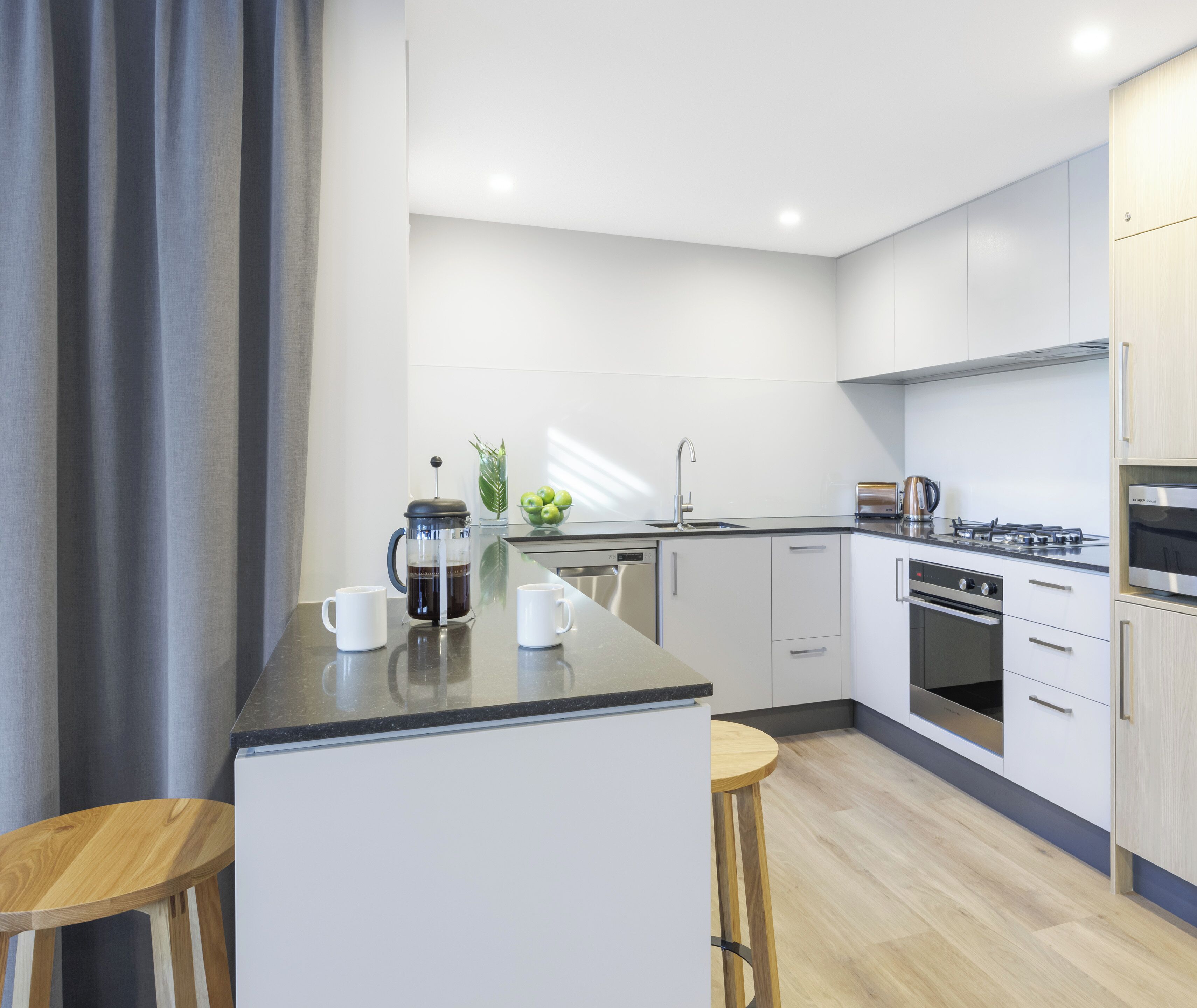 A modern kitchen with white cabinets, a black countertop, and stainless steel appliances.