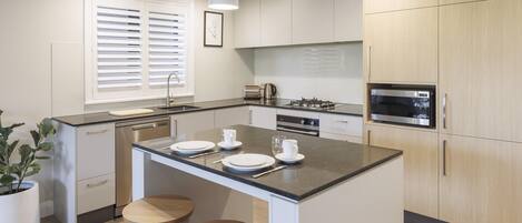 A modern kitchen with a central island, white cabinetry, and stainless steel appliances.