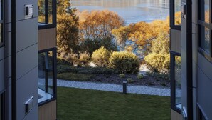 A modern building with large windows offering a view of a lake and mountains. - Avani Queenstown Hotel (Queenstown)