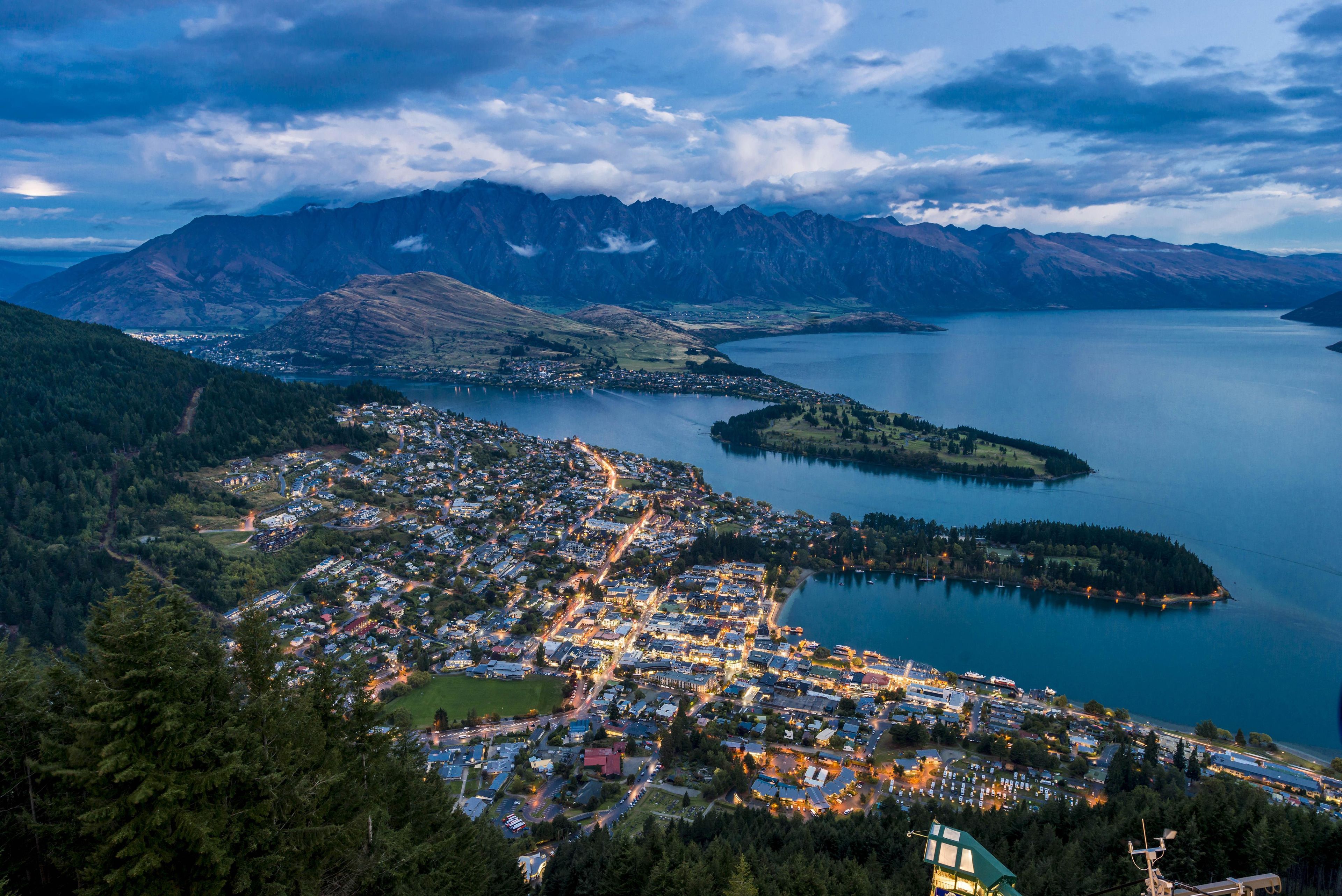 A coastal town with a dense cluster of buildings, a marina, and a lake surrounded by mountains.