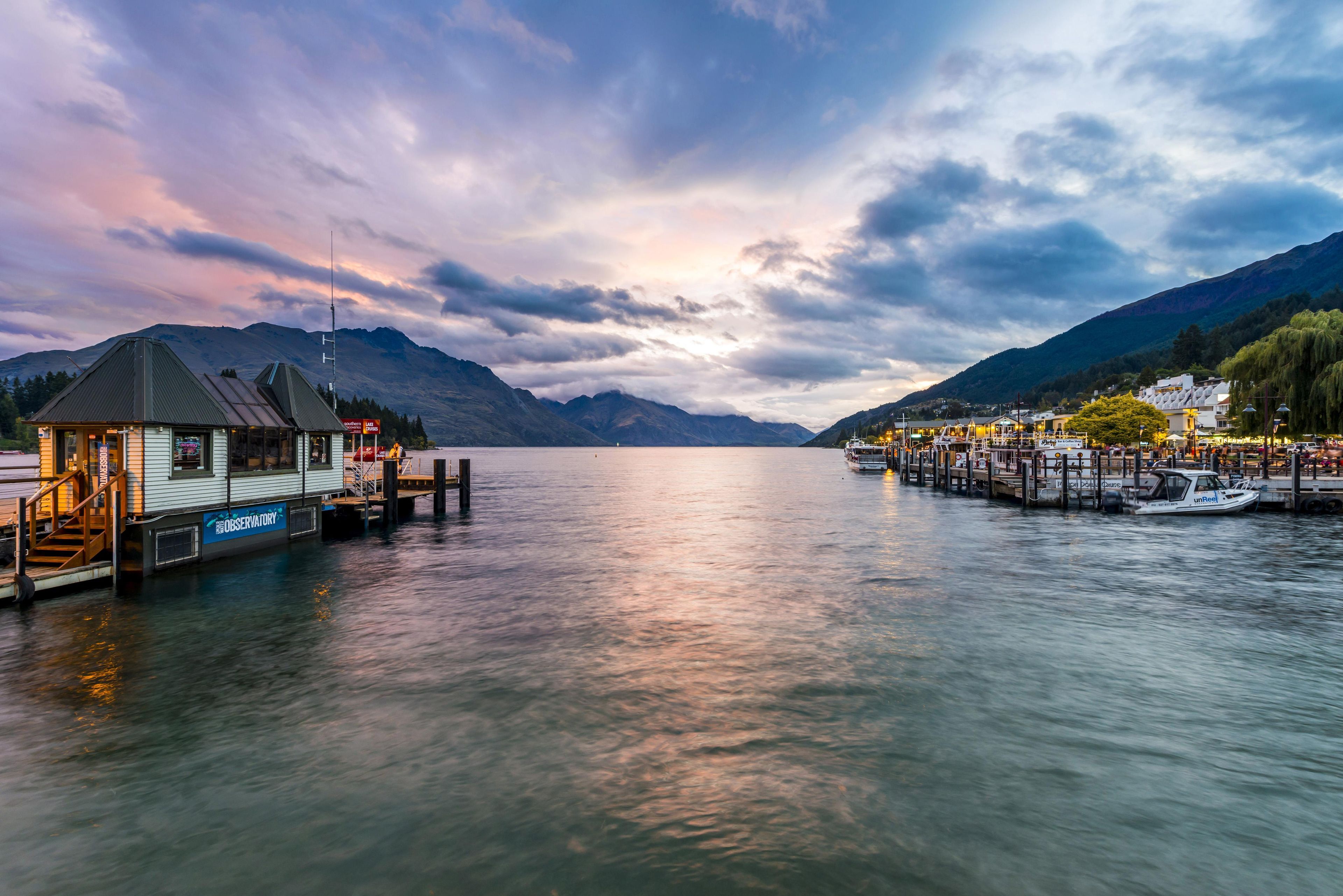 A docked boat, a pier, and a mountain range in the background.
