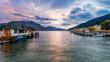 A docked boat, a pier, and a mountain range in the background.