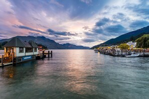 Un barco amarrado, un muelle y una cordillera al fondo.