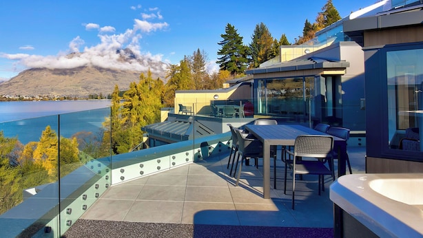A modern outdoor terrace with a glass balustrade overlooking a lake and mountains. - Avani Queenstown Hotel (Queenstown)