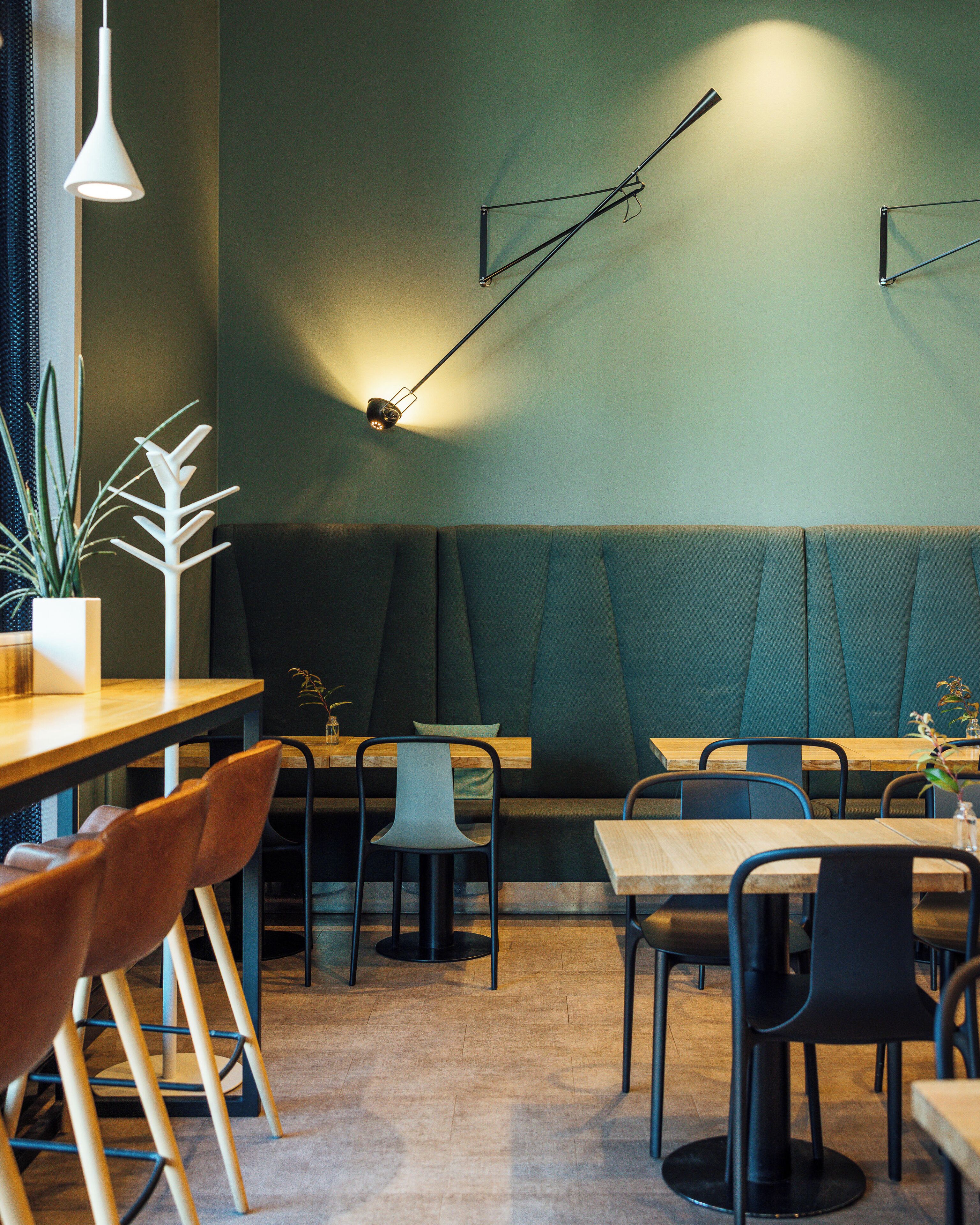 Un interior de restaurante moderno con cabinas, mesas de madera y sillas negras.