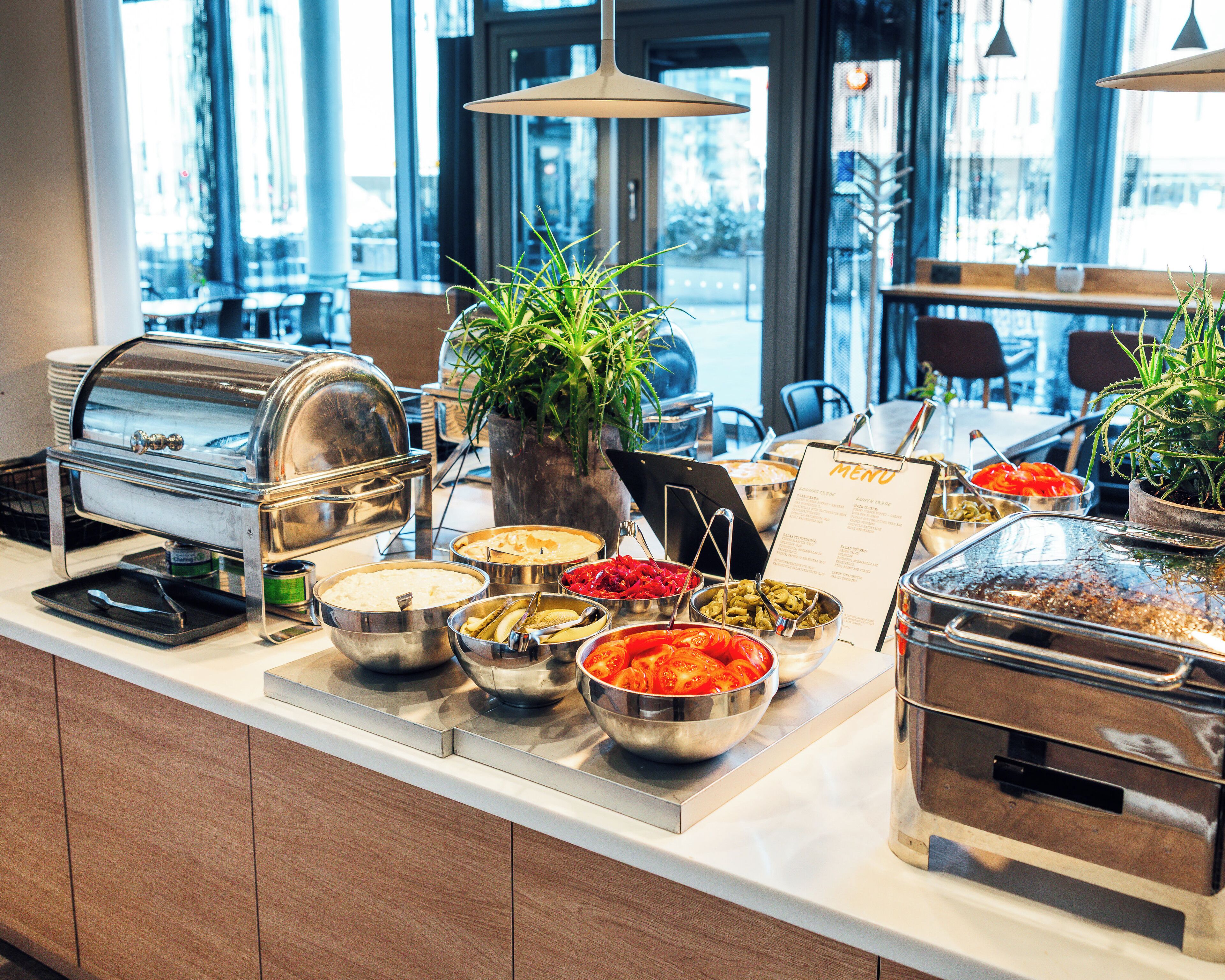A buffet setup with various food items and a menu sign.