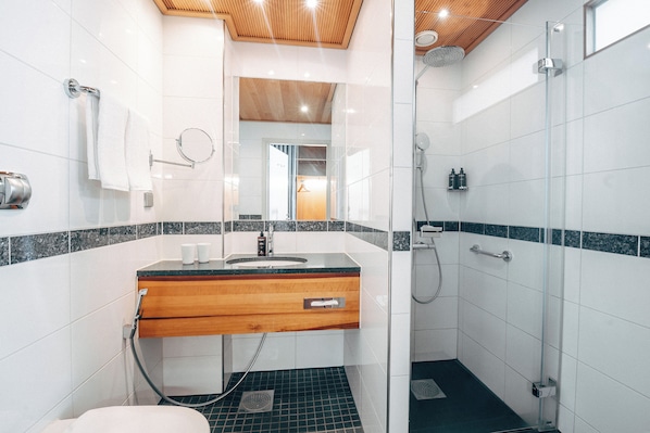 Un baño moderno con tocador de madera, cabina de ducha de vidrio y suelo de baldosas.