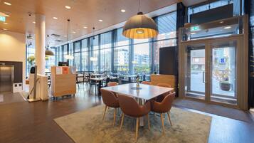 A modern interior with a large table and chairs, a reception desk, and large windows offering a view of the city.