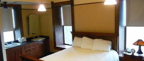 A bedroom with a wooden bed, a nightstand, a mirror, and a window.