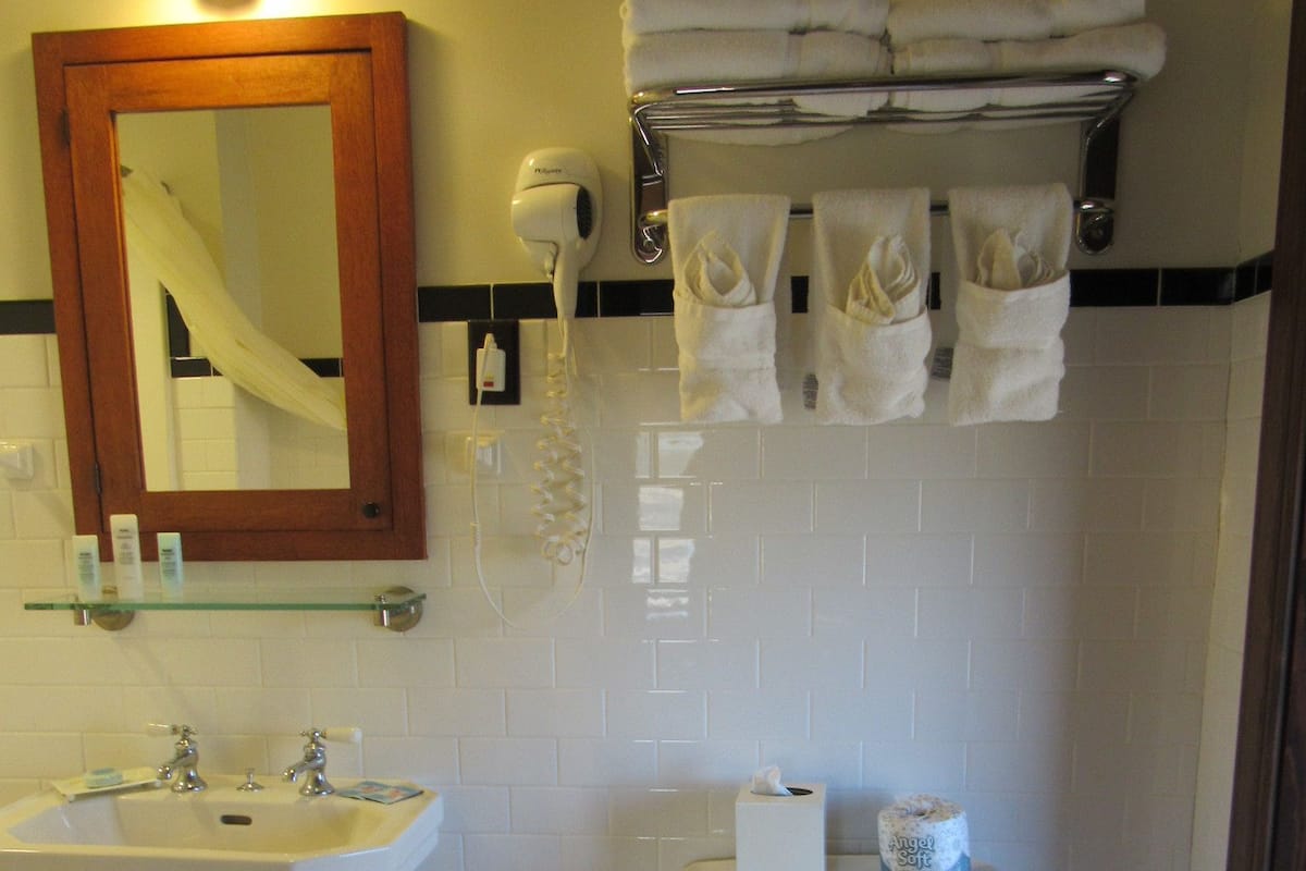 A bathroom with a sink, mirror, toilet, and a towel rack with towels.