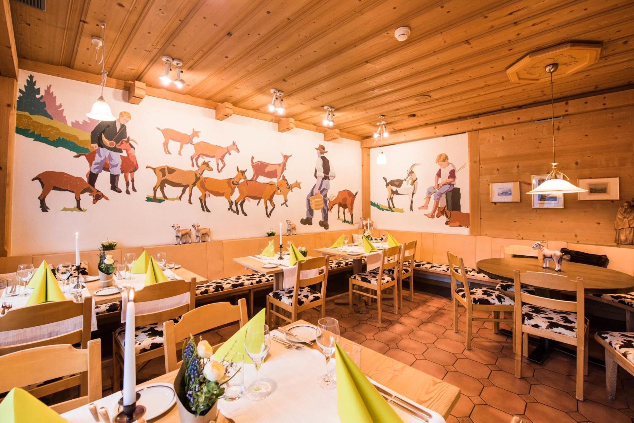 Un restaurante con interiores de madera, piso de baldosas hexagonales y mesas dispuestas con servilletas verdes y velas.