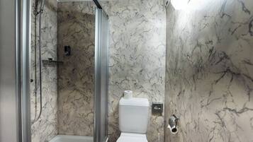 Une salle de bain avec douche, toilettes et murs en marbre.