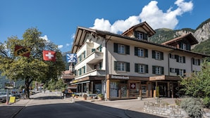 Un hotel con una bandera suiza, un cartel que dice Brienzerbühl y montañas al fondo.