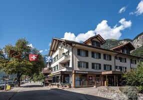 Un hotel con una bandera suiza, un cartel que dice Brienzerbühl y montañas al fondo.