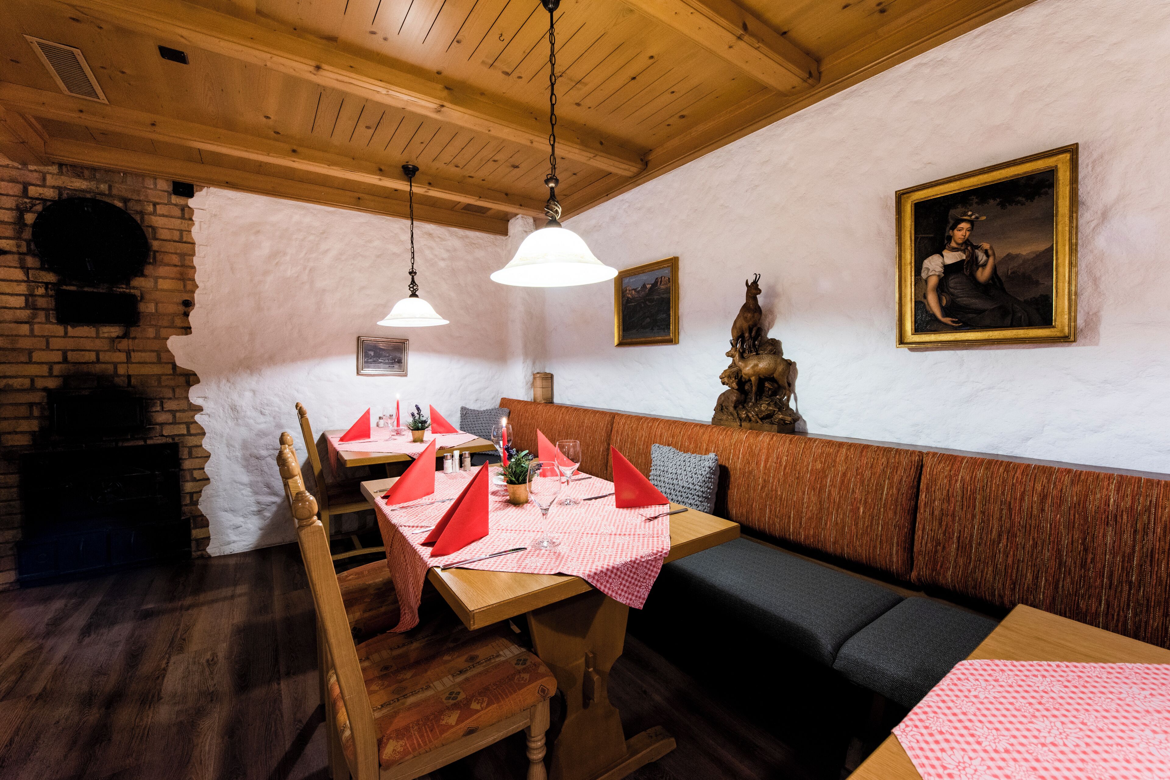 A rustic dining area with wooden tables, benches, and a brick wall.