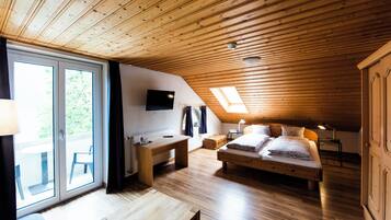 Quarto aconchegante com teto de madeira, uma cama, uma escrivaninha e uma televisão.
