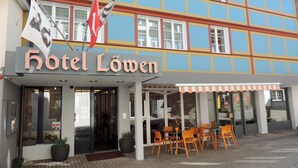 A hotel named Hotel Löwen with a colorful facade, outdoor seating area, and flags. - Hotel Löwen (Appenzell)