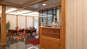 A hotel lobby with a reception desk, seating area, and a large window. - Hotel Löwen (Appenzell)
