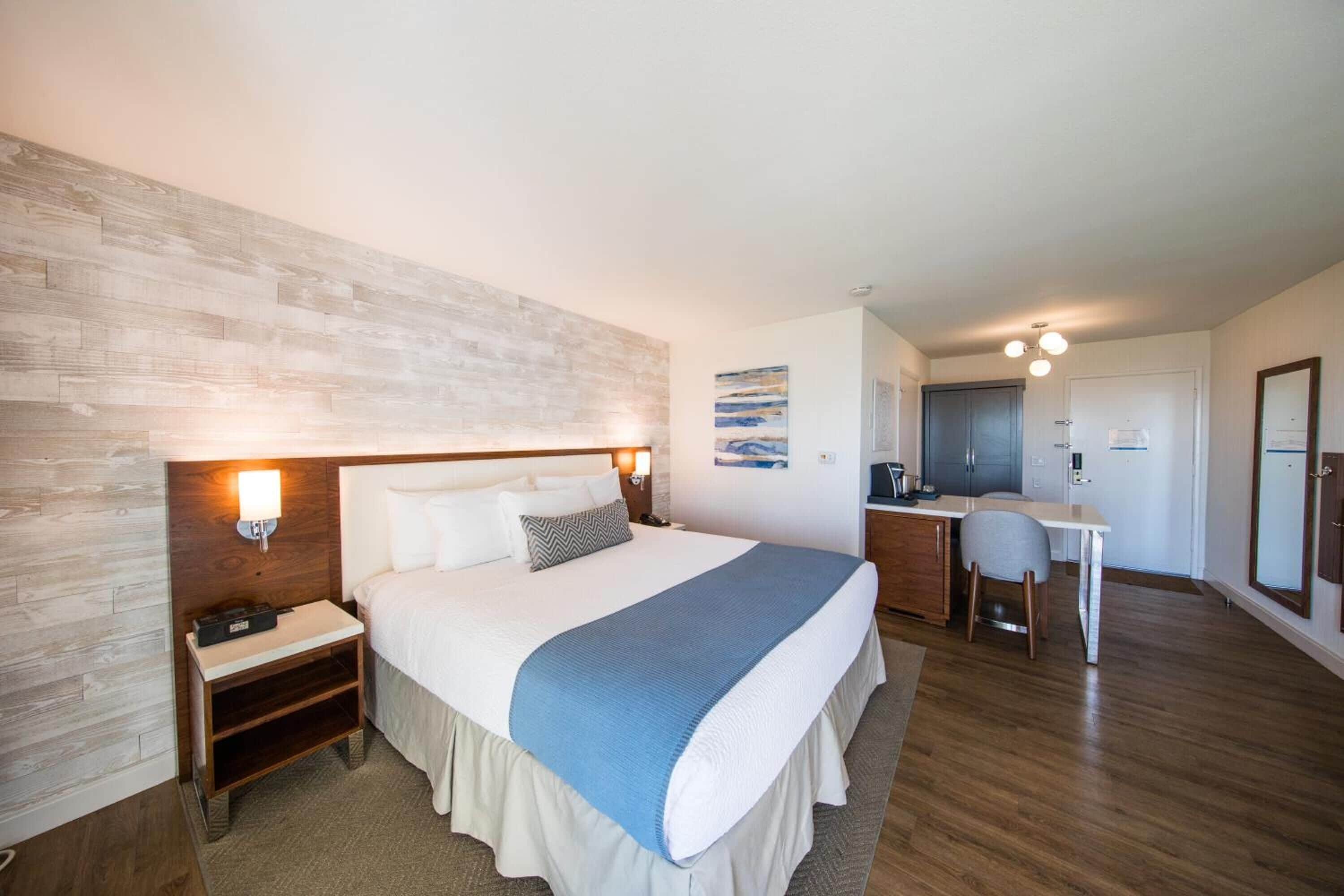 A hotel room with a large bed, bedside tables, a desk, and a chair.